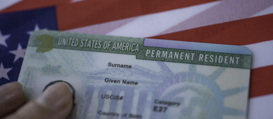 Permanent Resident Green card  of United states of America on flag of USA. Above close up view.