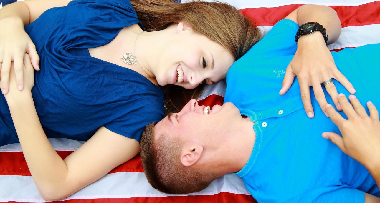 La nota trata sobre el proceso de obtención de la visa de prometido en Estados Unidos. La foto muestra una pareja con la bandera de este país.