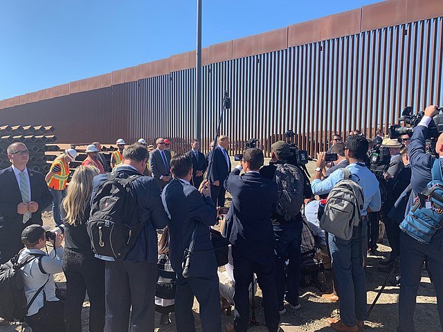 La nota es sobre la política de Trump y Biden en materia de derechos de los migrantes. La foto es de Trump en la frontera de México y Estados Unidos.