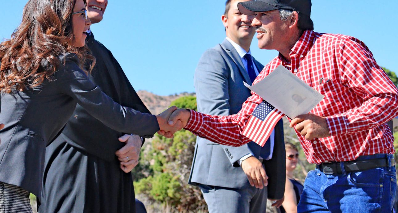 Nota explicando los requisitos para la ciudadanía americana 2021. La foto es de una ceremonia de naturalización realizada recientemente.