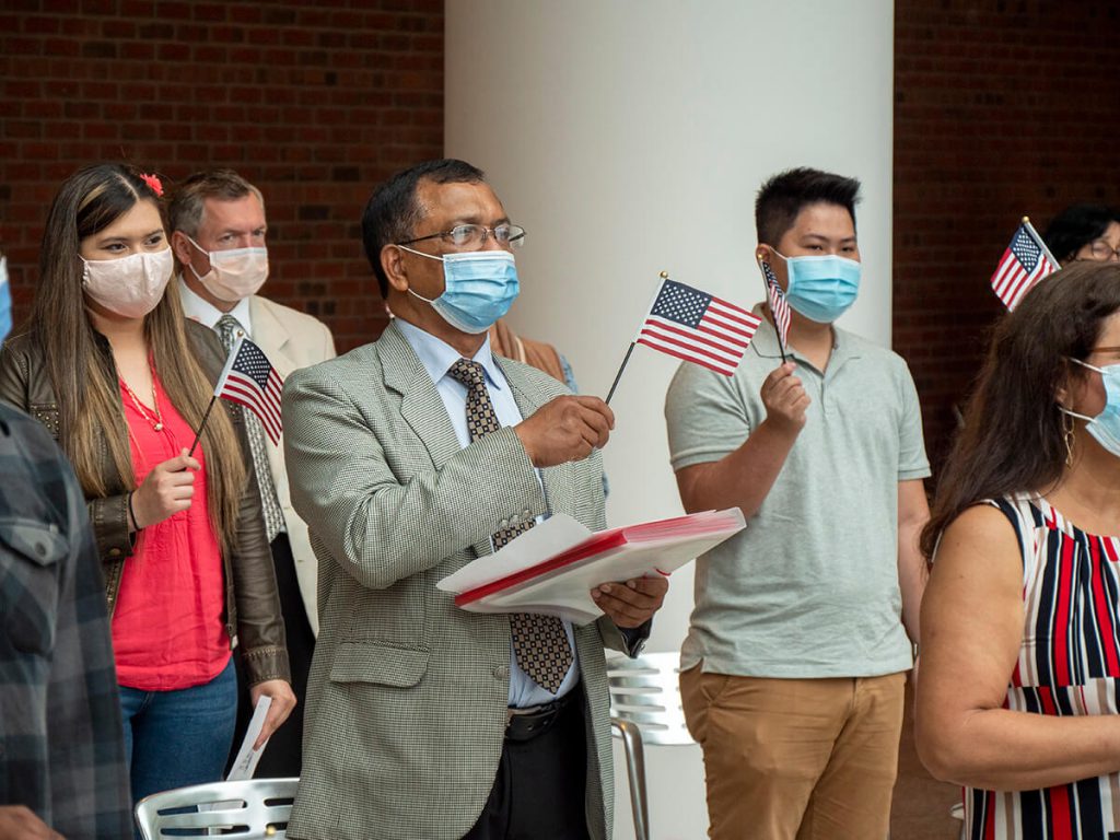 Nota explicando los requisitos para la ciudadanía americana 2021. La foto es de una ceremonia de naturalización realizada recientemente.